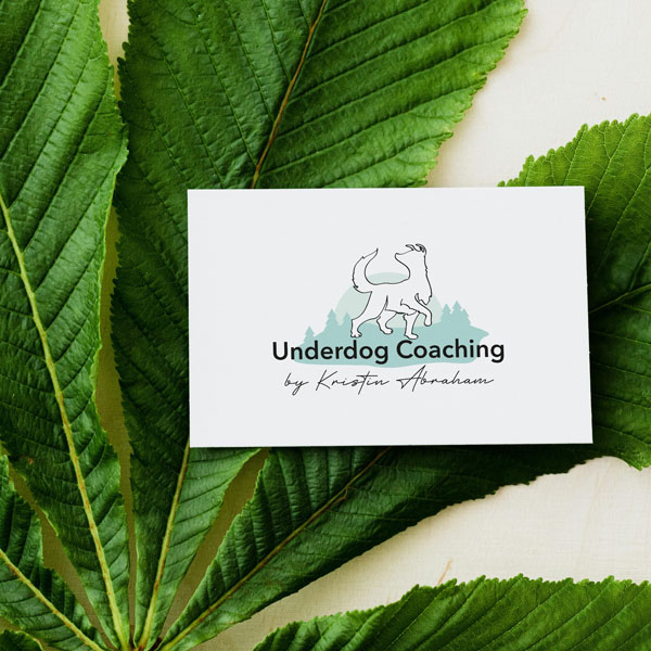 Visitenkarte Underdog Coaching liegend auf gruenem Blatt
